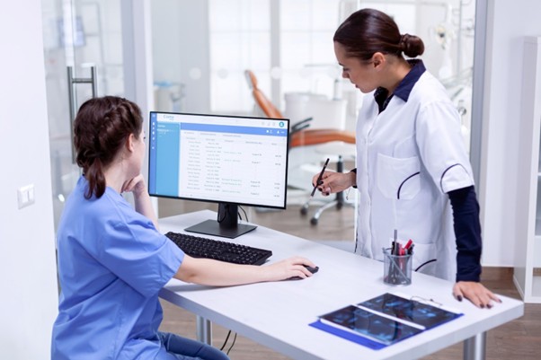 Veterinary staff reviewing patient records on a computer in a clinic.