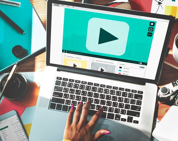 Person using a laptop with a YouTube play button, highlighting video marketing and content creation